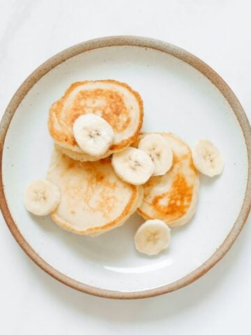 overhead view of simple pancakes for baby on a plate with sliced bananas