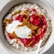 a bowl of oatmeal topped with Greek yogurt, peanut butter, and strawberries