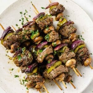 four grilled beef kabobs on a plate