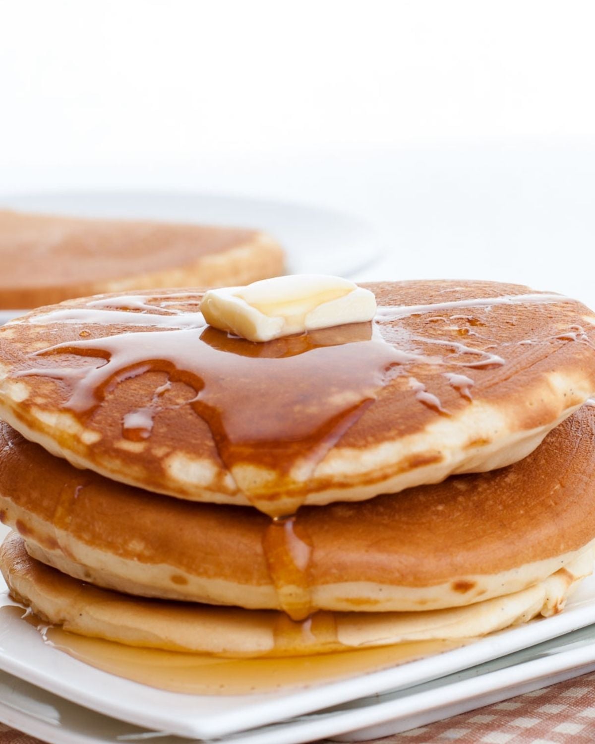 stack of banana ricotta pancakes on a plate topped with butter and pancake syrup