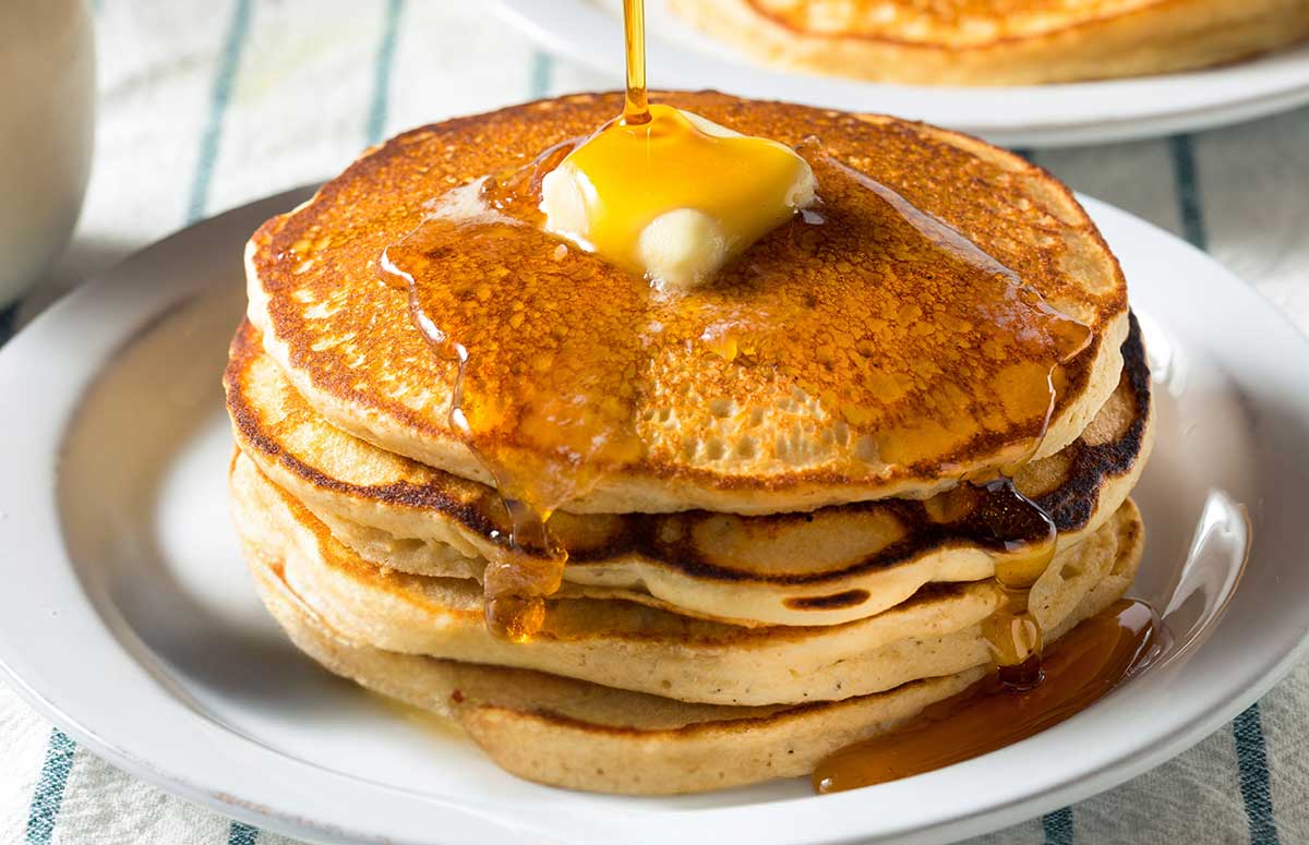 stack of buttermilk pancakes topped with butter and syrup