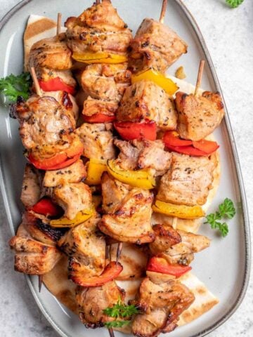 top view of a white dish with five pork kabobs