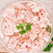 top view of a salmon salad in a bowl, topped with green leaves
