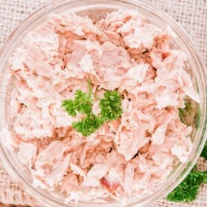 top view of a salmon salad in a bowl, topped with green leaves