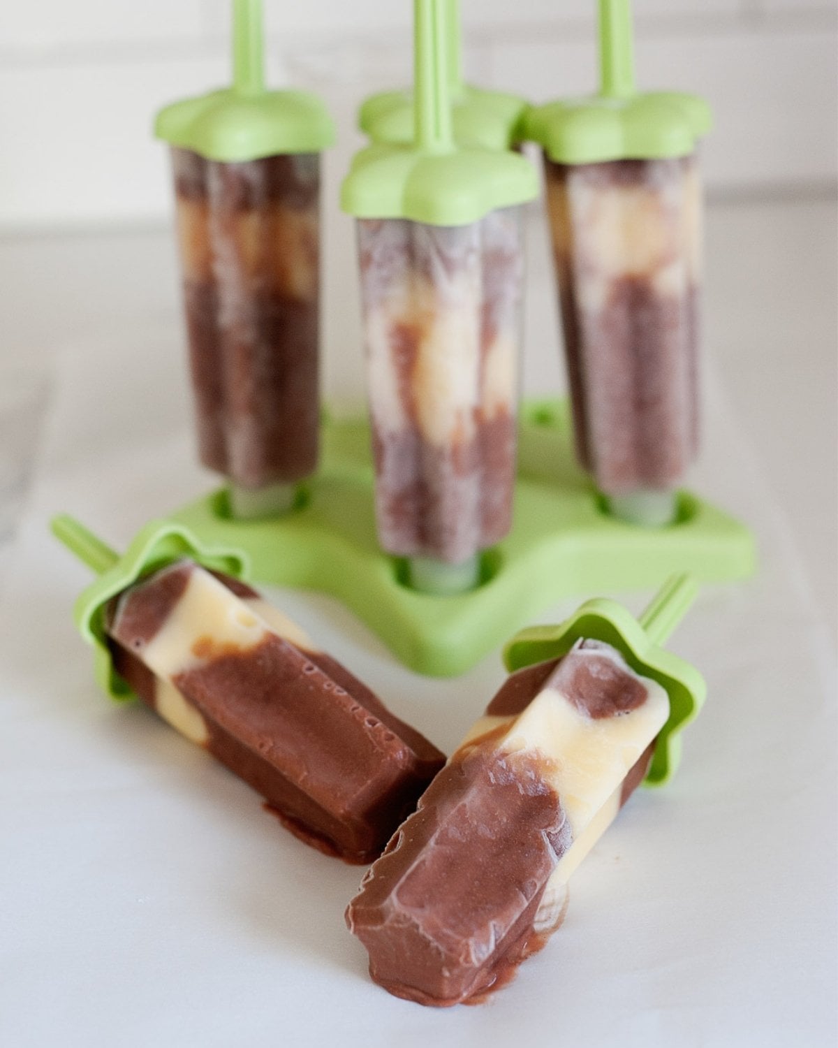 four banana chocolate pudding pops in their molds and two more with no mold over the counter