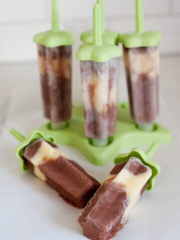 four banana chocolate pudding pops in their green molds and two more with no mold over the counter