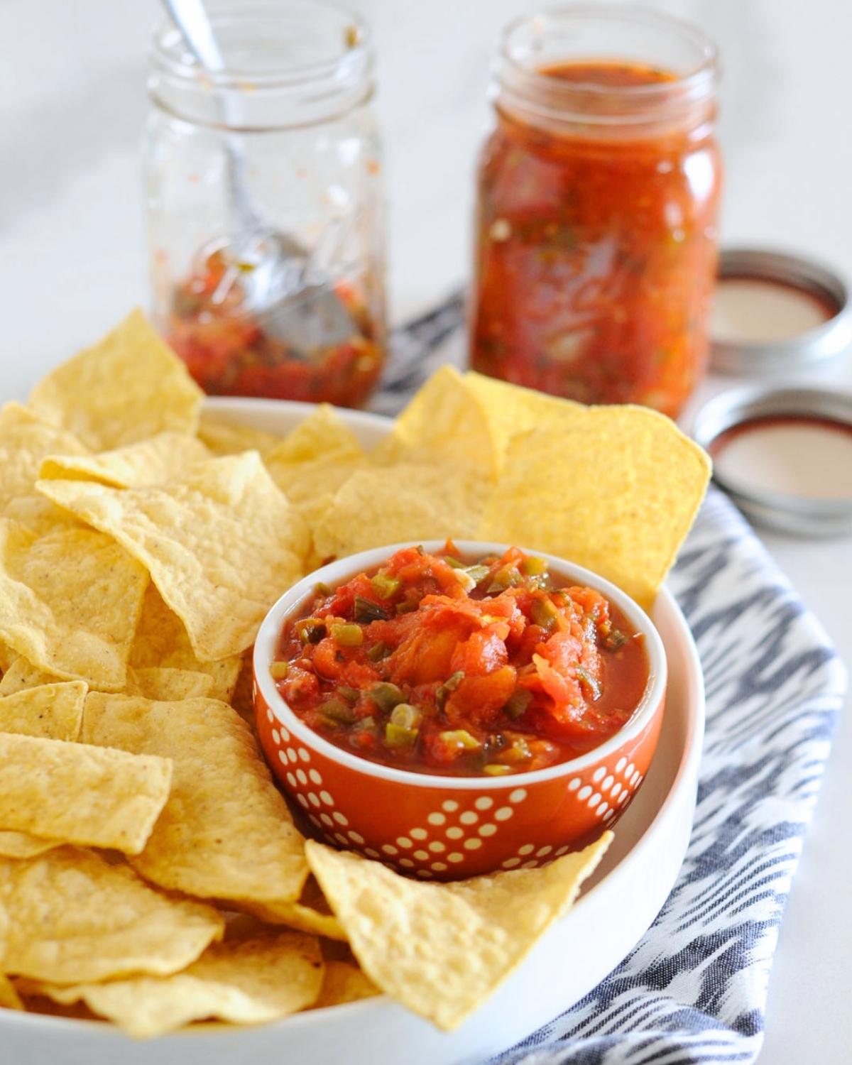 hero of this homemade canned salsa recipe in a dish with chips and some open jars of salsa in background