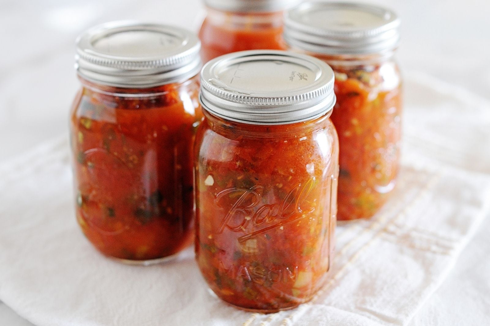 4 pint jars filled with homemade canned salsa