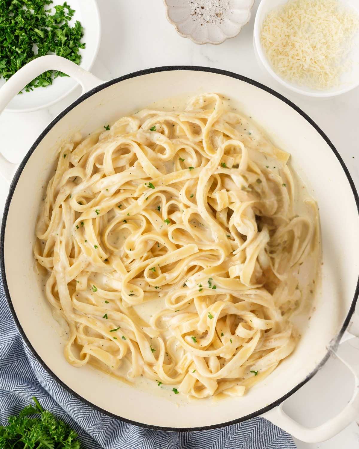 top view of a pot with fettuccine pasta coated with creamy Alfredo sauce