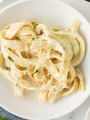 fettuccine pasta coated with creamy Alfredo sauce on a white dish