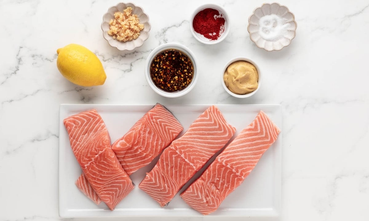 ingredients to make hot honey salmon: four salmon fillets, lemon, mustard, garlic, paprika, and salt