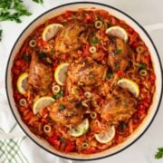 overhead view of the finished recipe for Spanish chicken and rice, a seasoned chicken and rice dish garnished with lemon slices.