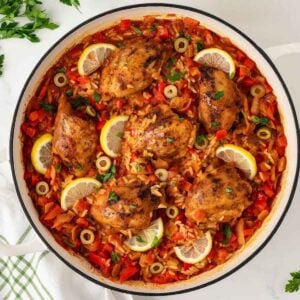 overhead view of the finished recipe for Spanish chicken and rice, a seasoned chicken and rice dish garnished with lemon slices.