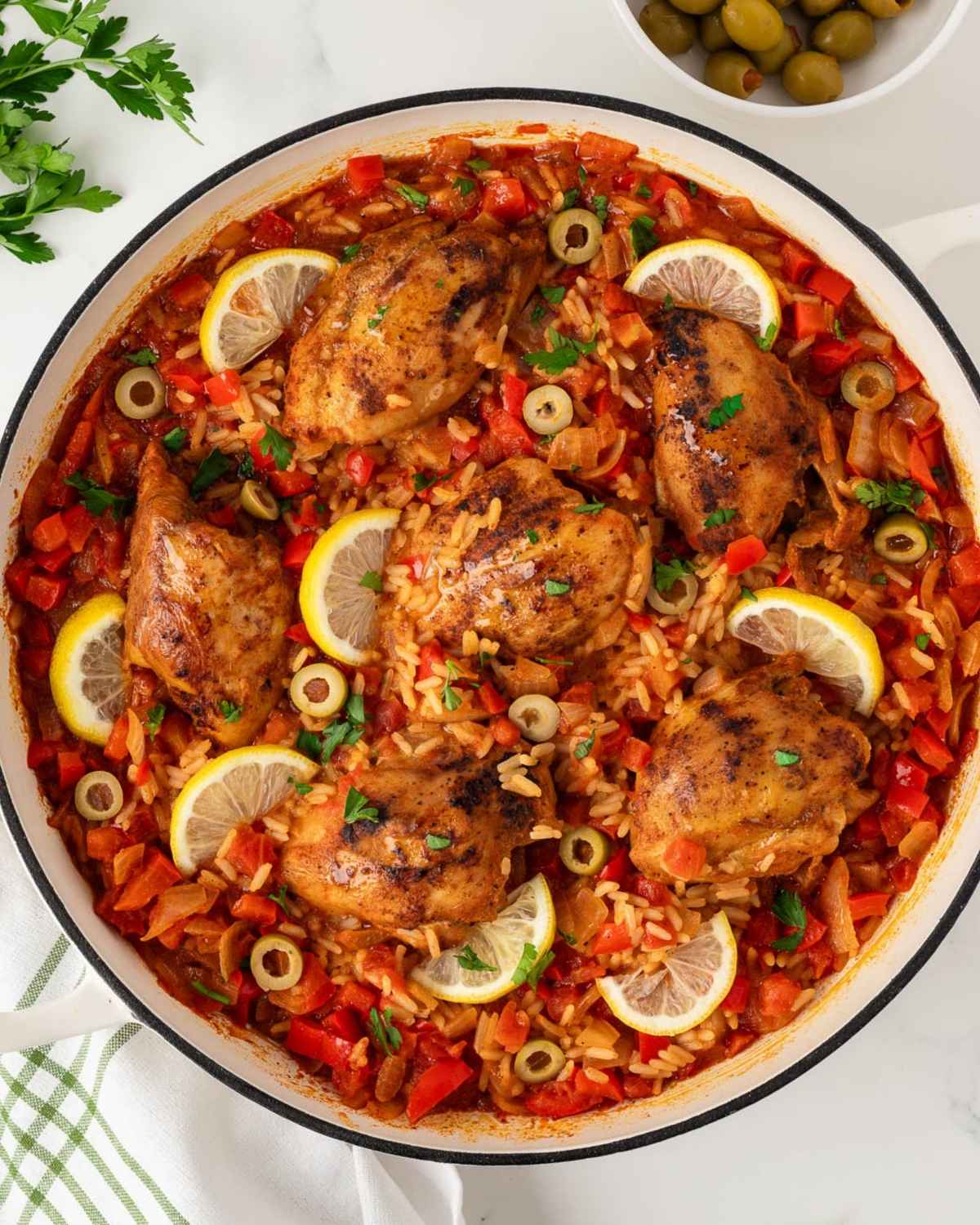 overhead view of the finished recipe for Spanish chicken and rice, a seasoned chicken and rice dish garnished with lemon slices.