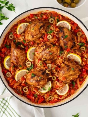 overhead view of the finished recipe for Spanish chicken and rice, a seasoned chicken and rice dish garnished with lemon slices.