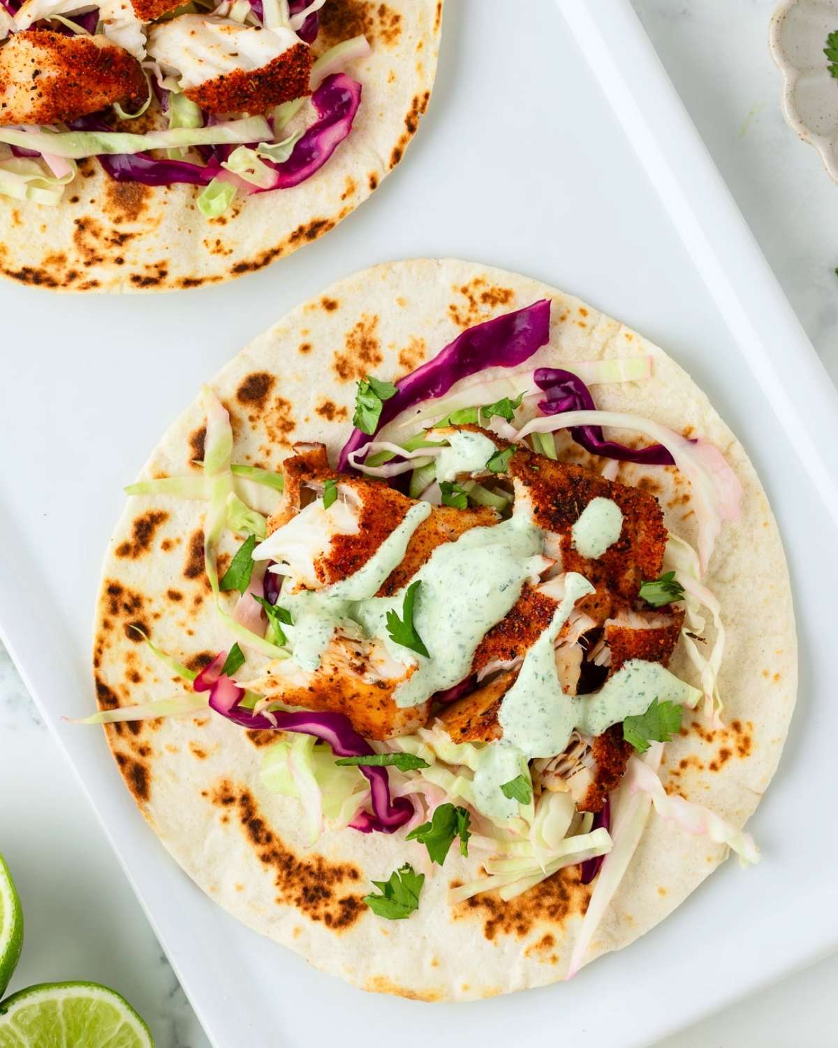 fish taco with cilantro sauce and slaw on a white tray