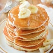 a stack of applesauce pancakes topped with syrup and banana slices