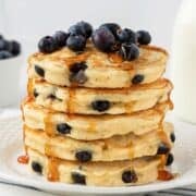 front view of fluffy blueberry protein powder pancakes topped with blueberries and pancake syrup