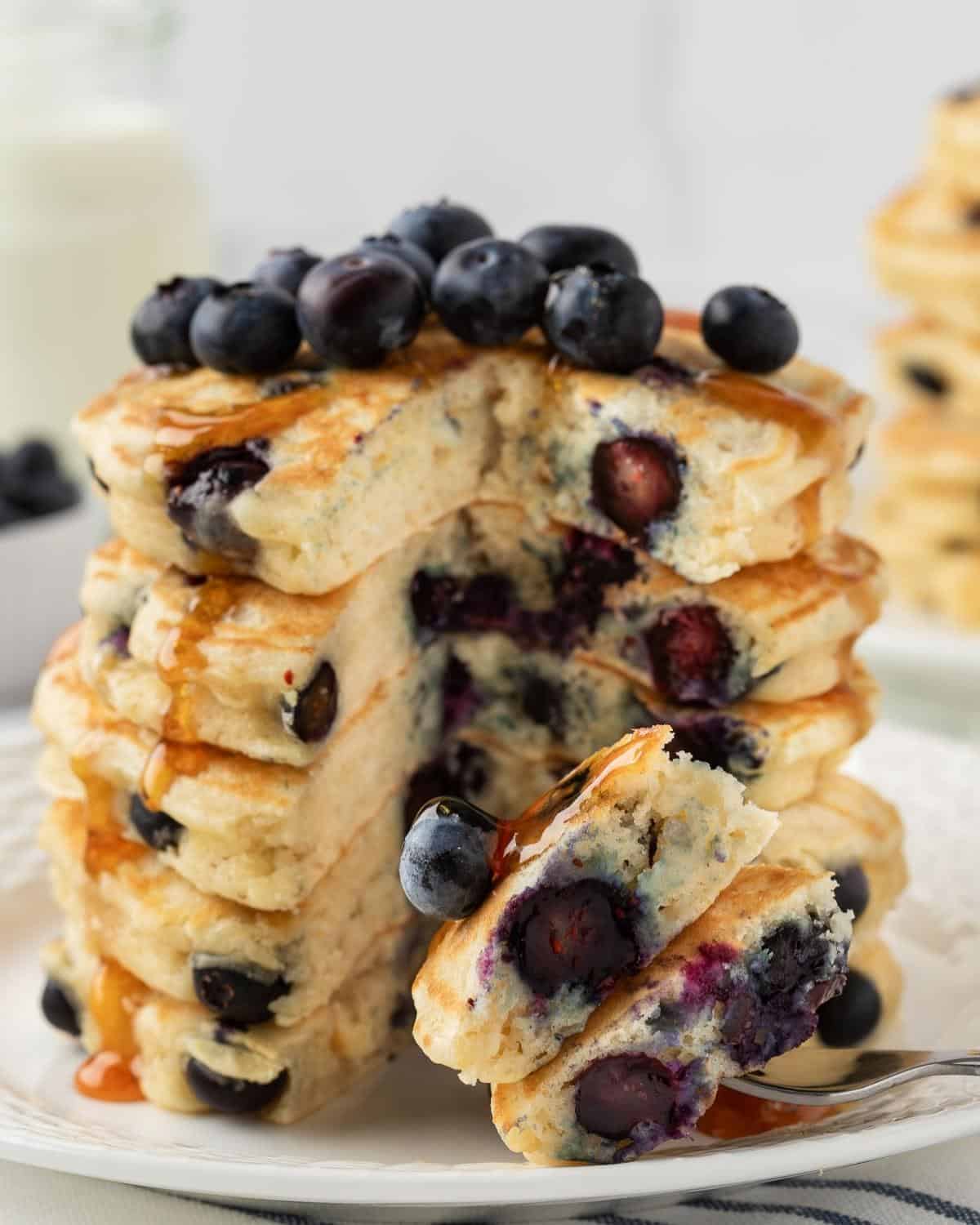 front view of a stack of blueberry protein pancakes sliced to show fluffy texture and blueberries inside