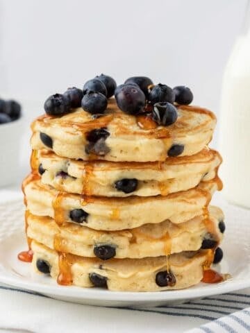 front view of fluffy blueberry protein powder pancakes topped with blueberries and pancake syrup