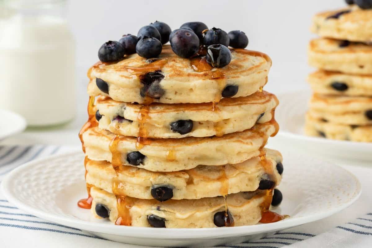 front view of fluffy blueberry protein powder pancakes topped with blueberries and pancake syrup