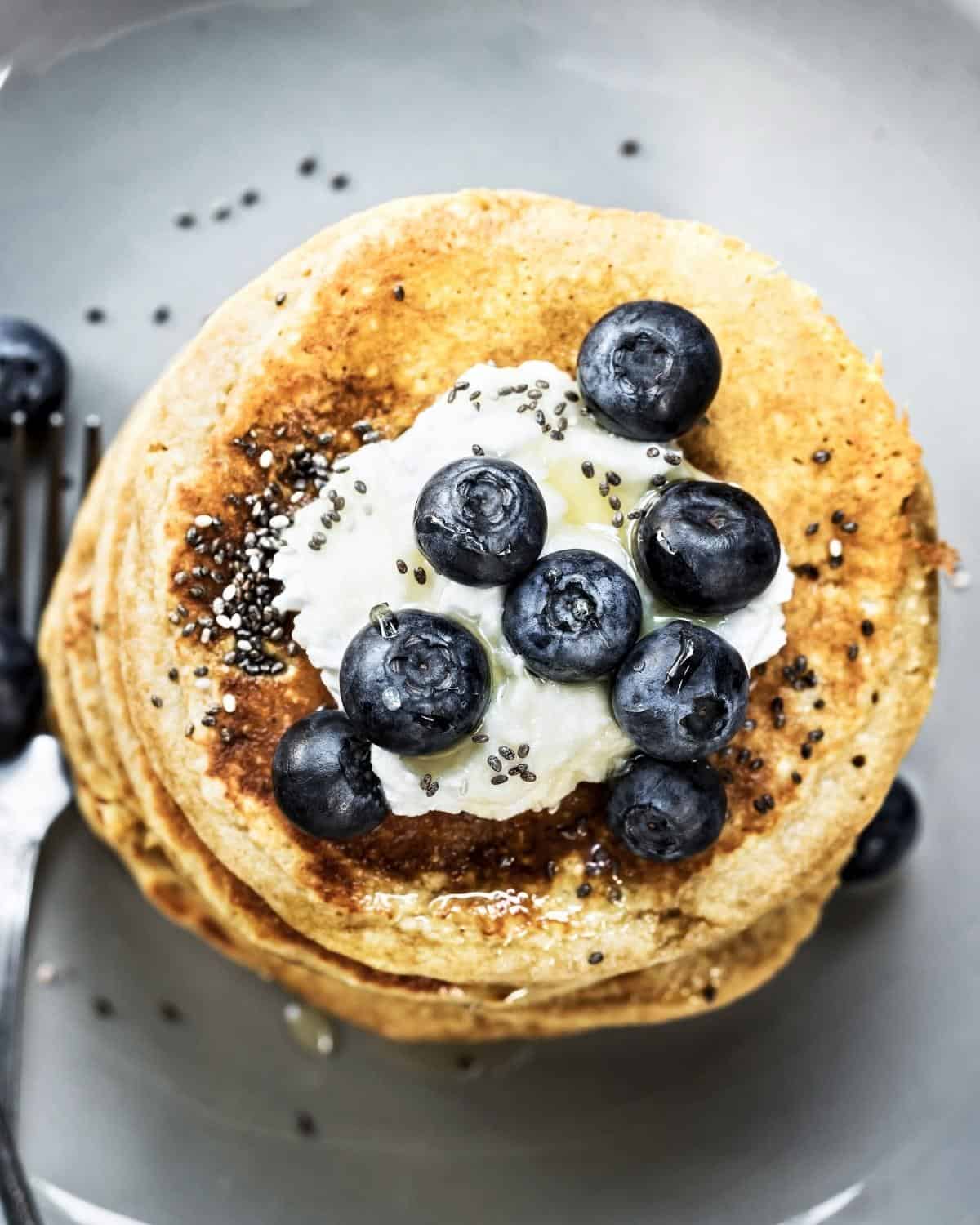 overhead voew of a stack of chia pancakes topped with yogurt, blueberries, and chia seeds
