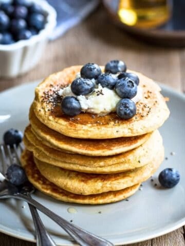 Stack of chia pancakes topped with yogurt, blueberries, and chia seeds