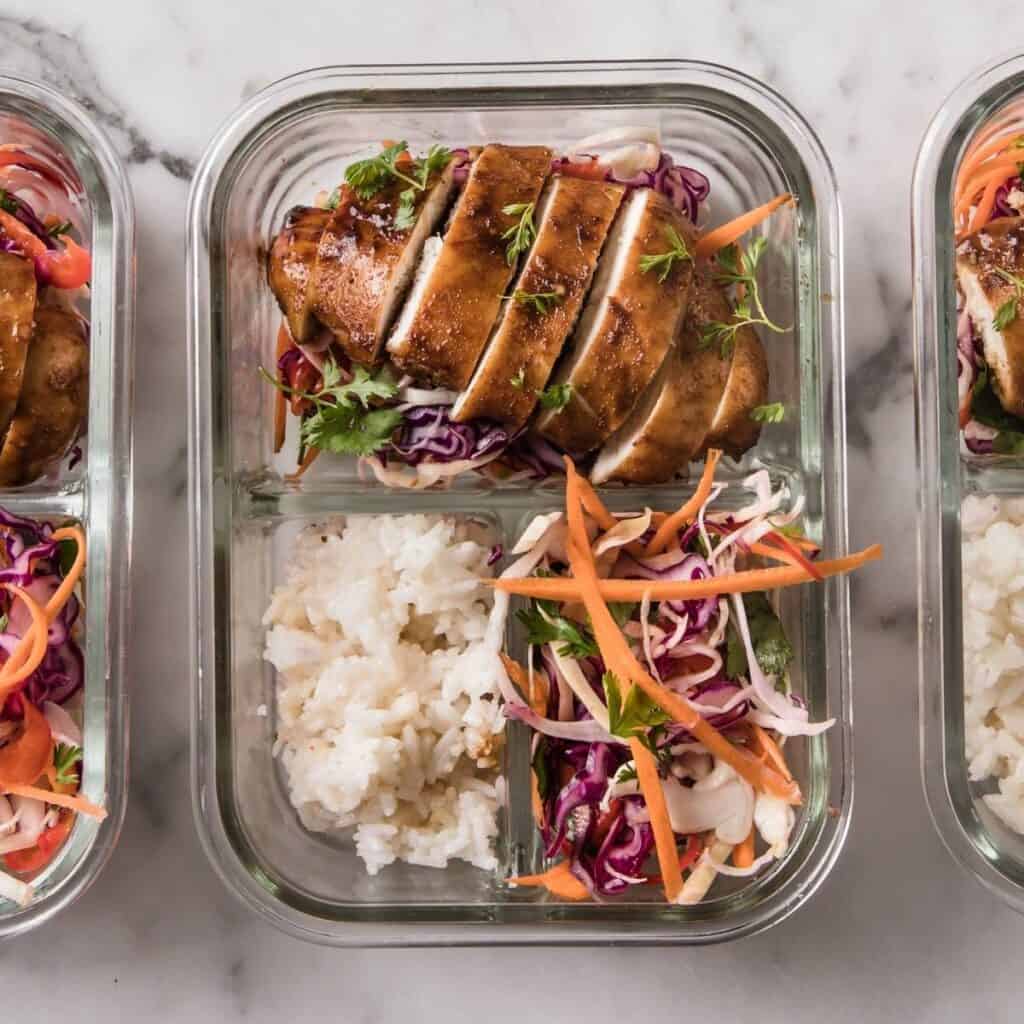 glass lunch container with Korean chicken, rice, and veggies