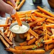 front view of sweet potatoes cooked in the air fryer being dipped in mayo