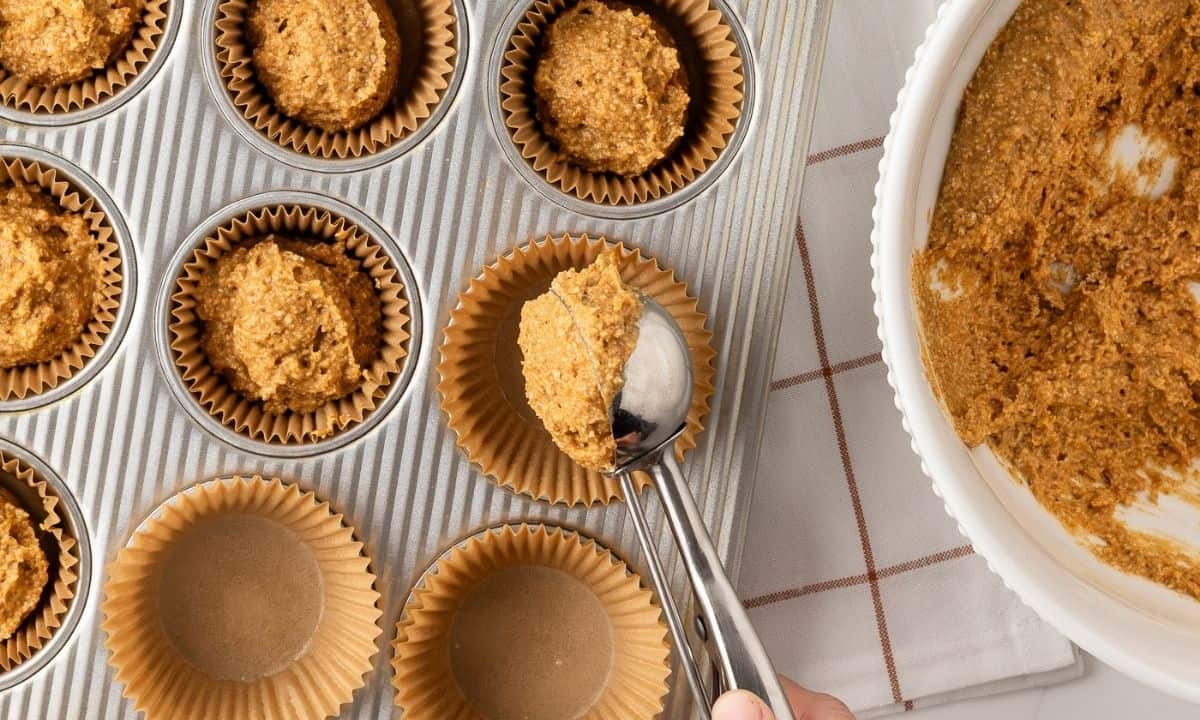 filling a baking pan lined with muffin liners with pumpkin chocolate chip batter