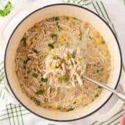 overhead view of a pot of white chicken chili and a hand grabbing a spoonful of it