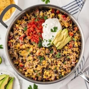 taco skillet with tortilla chips and avocado on the side