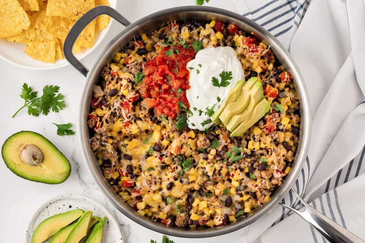taco skillet with tortilla chips and avocado on the side