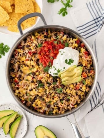 taco skillet with tortilla chips and avocado on the side