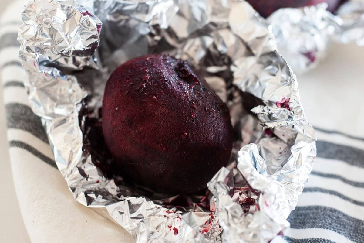 close up of a whole roasted beet inside foil