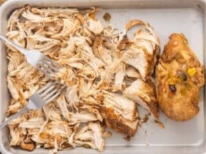 shredding the cooked chicken on a cutting board