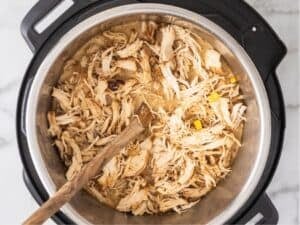 adding the shredded chicken back into the instant pot once it's cooked