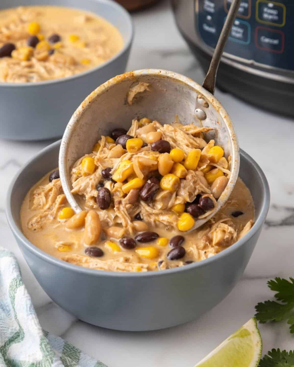 using a ladle to fill a bowl with white chicken chili made in the pressure cooker