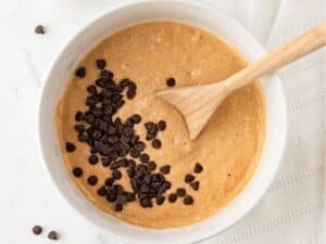 chocolate chips on top of a bowl of pumpkin pancake batter