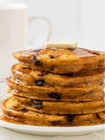 a stack of pumpkin protein pancakes topped with butter and syrup