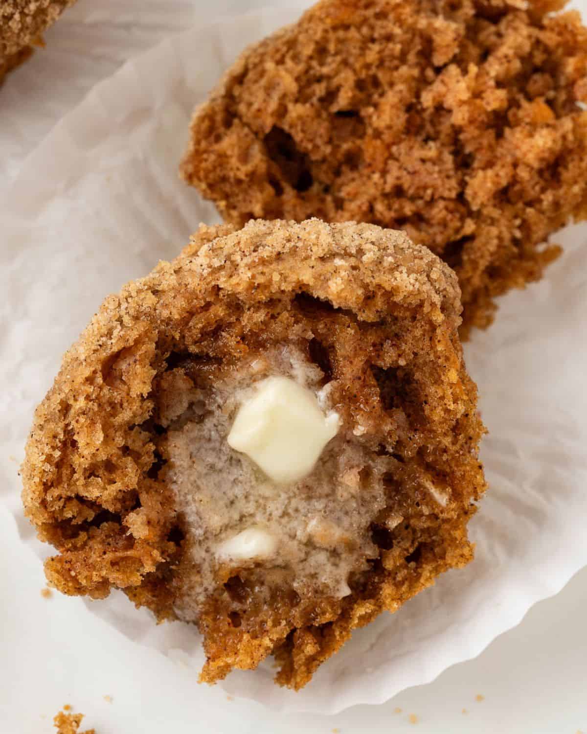 a sweet potato muffin split open with a pat of butter melting to show crumbly and soft texture
