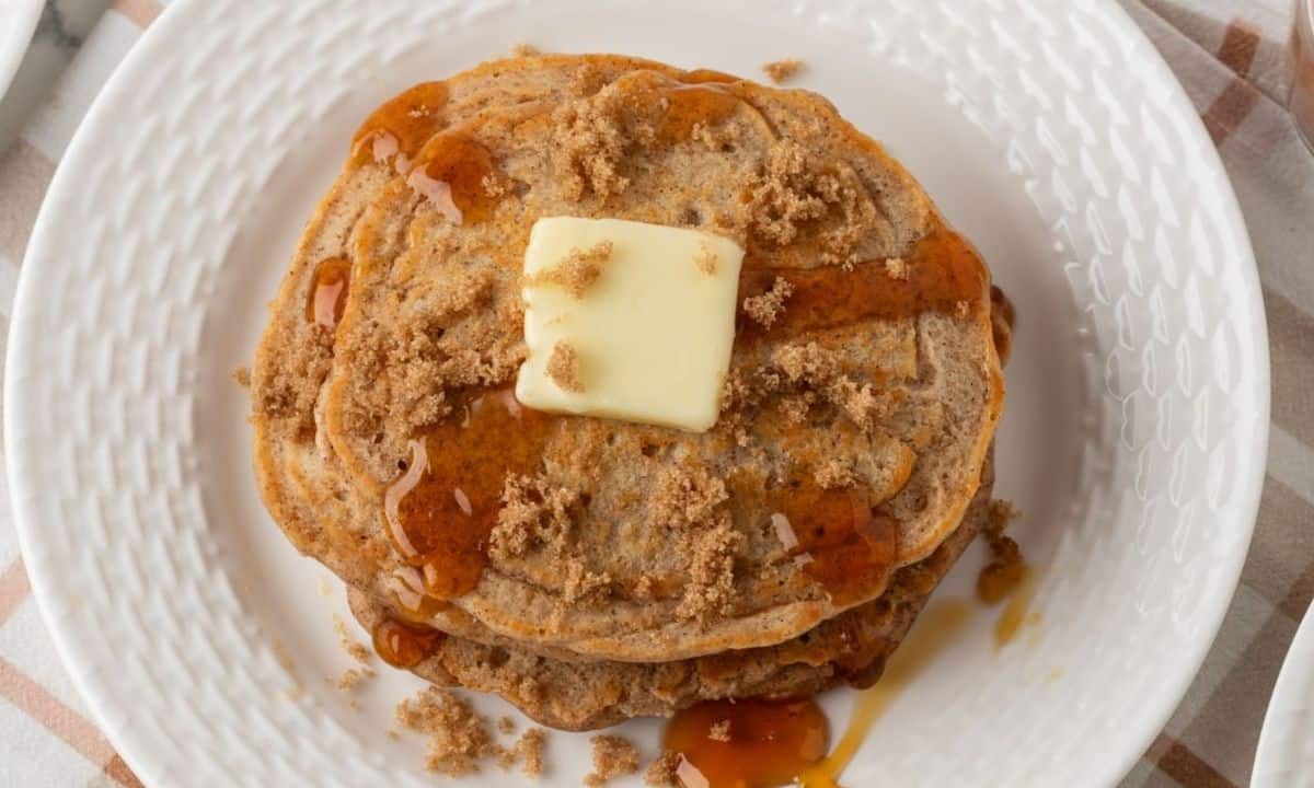 overhead view of a stack of brown sugar pancakes topped with butter and syrup