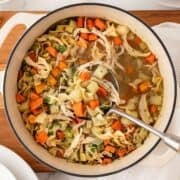 a pot of chicken noodle soup with potatoes