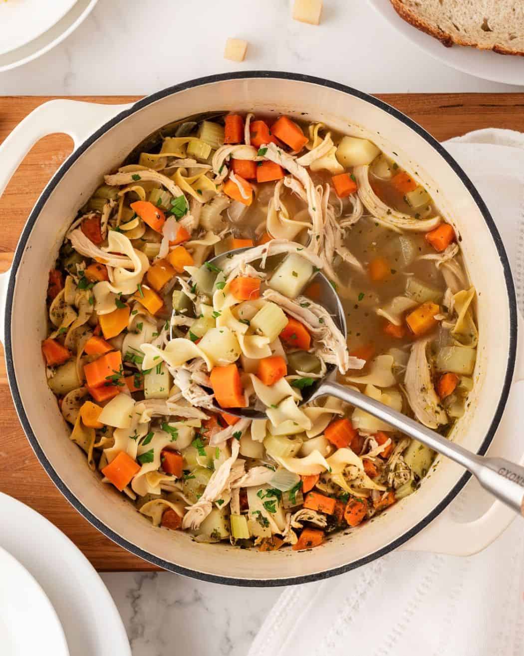 a pot of chicken noodle soup with potatoes